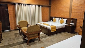 A hotel room with a bed, a chair, a nightstand, and a curtain. - Kaveri Resort & Spa (Avudangawa)