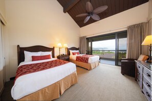 Une chambre d’hôtel avec deux lits, un ventilateur de plafond, un balcon avec vue et une commode.