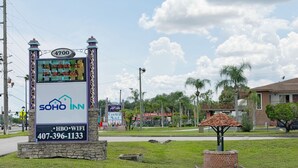 Un cartel de hotel con una pantalla digital, una base de piedra y una pequeña construcción de ladrillo.