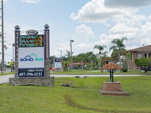 Un cartel de hotel con una pantalla digital, una base de piedra y una pequeña construcción de ladrillo.