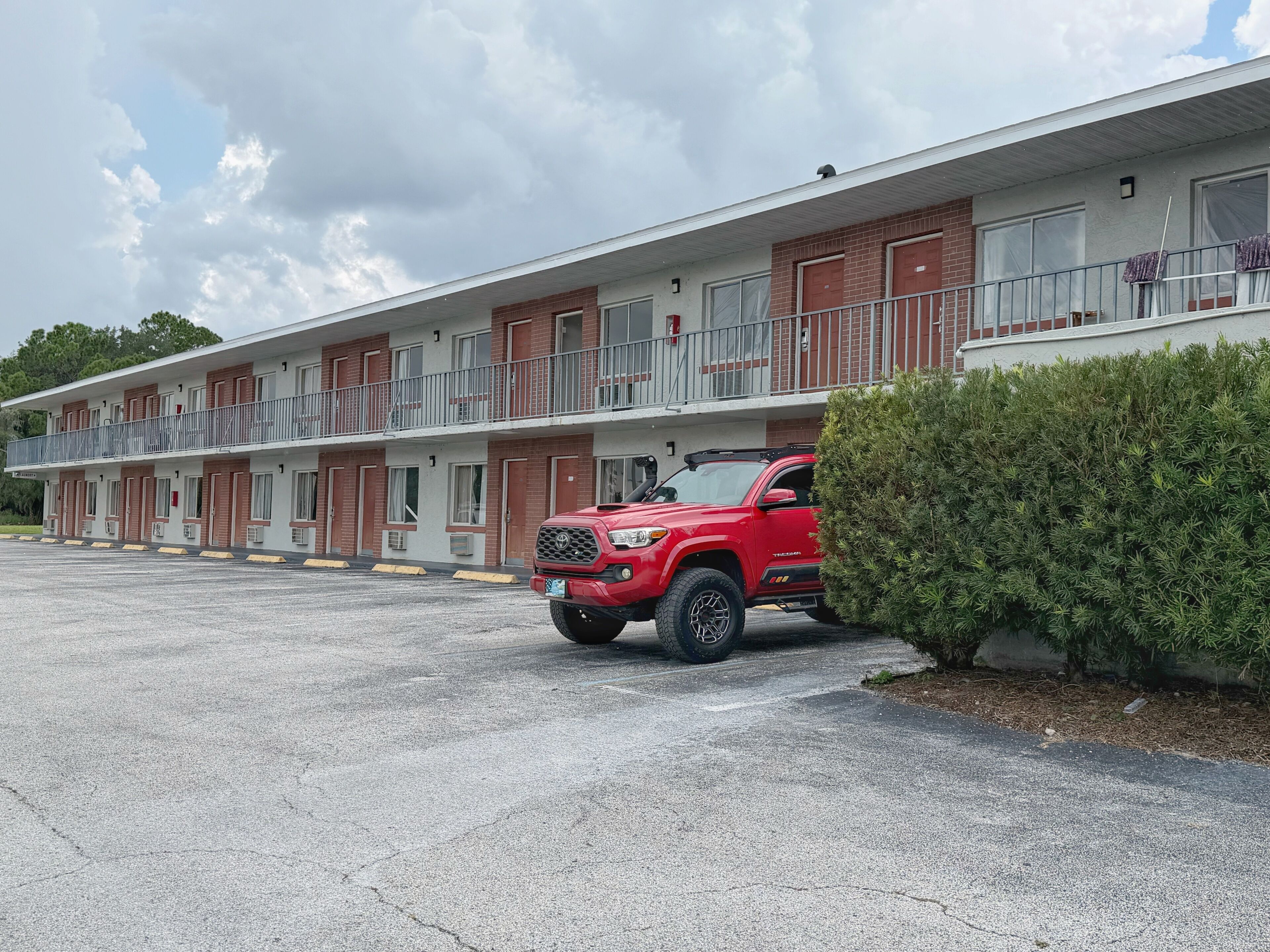 Um motel com uma SUV vermelha estacionada em frente.