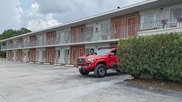 Um motel com uma SUV vermelha estacionada em frente.