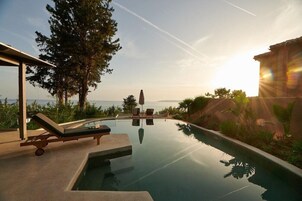 Una piscina infinita con sillones de descanso, vista al mar y cielo despejado.