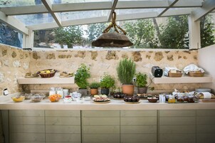 Una cocina con pared de piedra, plantas en macetas y diversos alimentos sobre la encimera.
