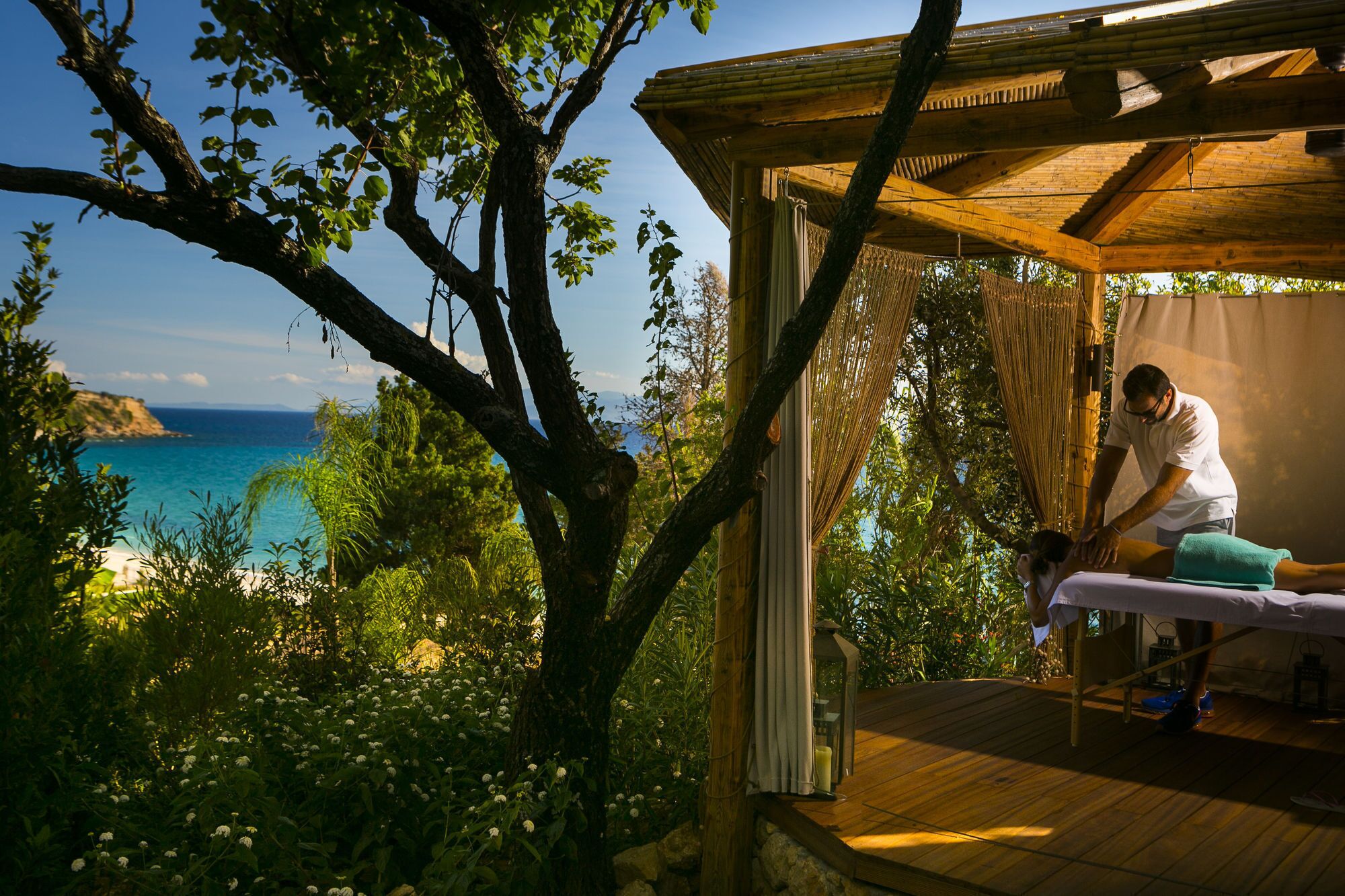 A wooden deck with a massage table and a person attending to a client.