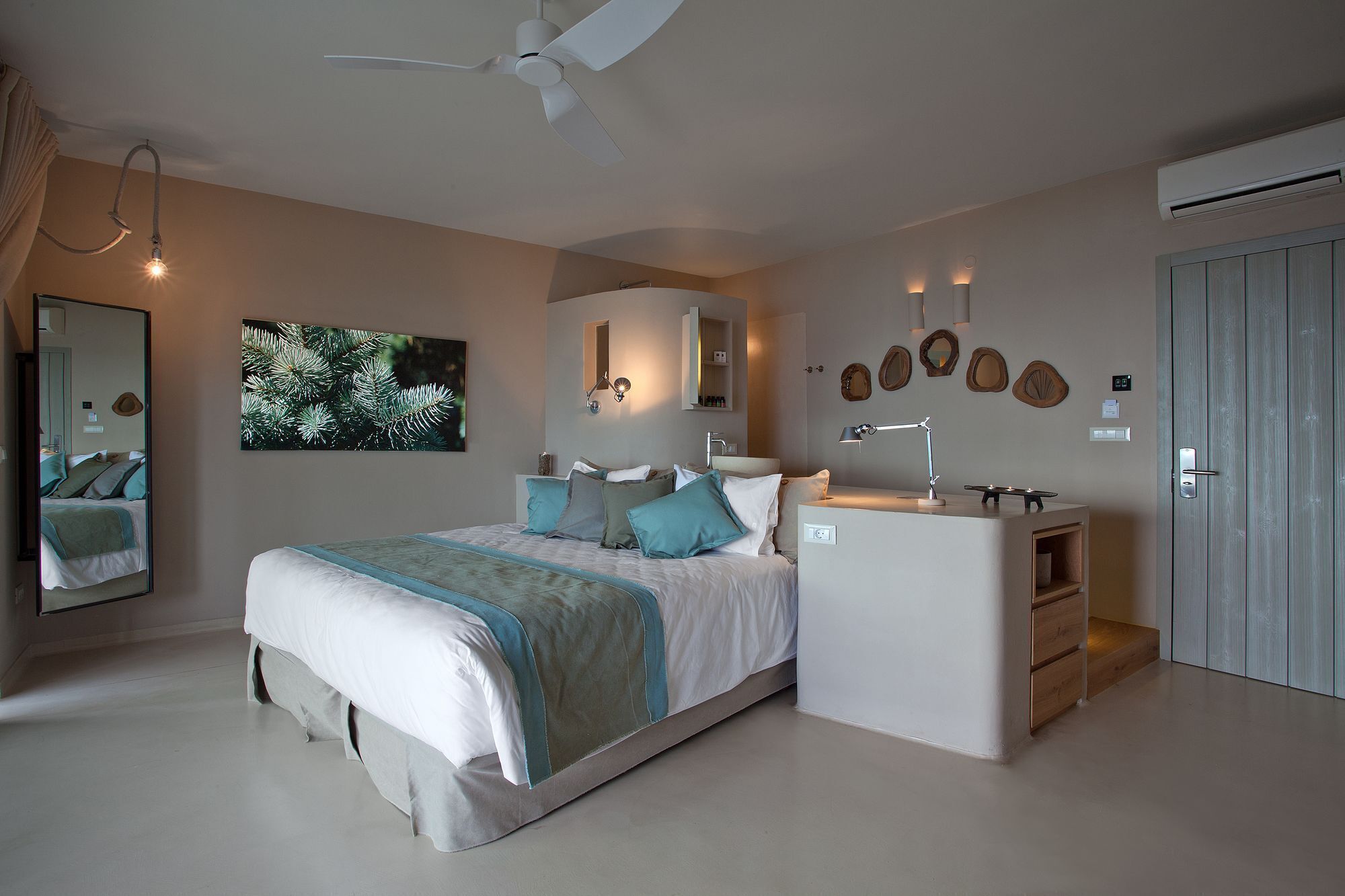 A modern bedroom with a bed, bedside table, mirror, and a ceiling fan.