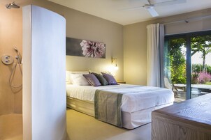 Un dormitorio con cama, mesita de noche, ducha, ventana con cortinas y vista a zonas verdes.
