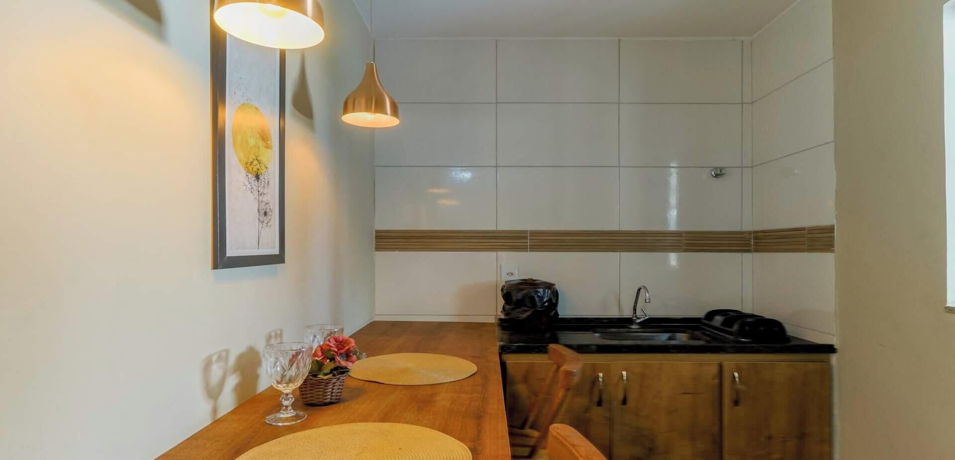 A compact kitchen with white cabinets, a wooden countertop, and a black sink.