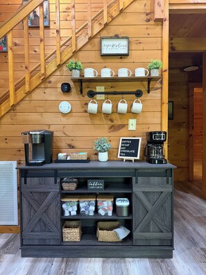 A wooden interior with a coffee station featuring a coffee maker, mugs, and a sign indicating coffee and tea options. - Bear Haven | Cozy Cabin•Hot Tub•Near Pigeon Forge (Pigeon Forge)