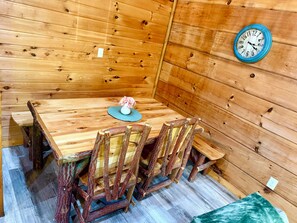 A wooden dining table with chairs, a clock on the wall, and a vase with flowers. - Pet-Friendly Cabin Near Pigeon Forge & Gatlinburg (Pigeon Forge)