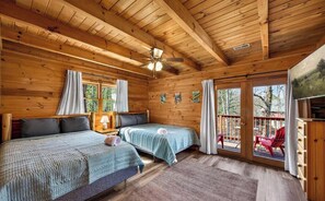 A cabin with two beds, a ceiling fan, and a balcony with red chairs. - Pet-Friendly Cabin Near Pigeon Forge & Gatlinburg (Pigeon Forge)