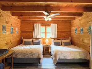 A cabin with two beds, a ceiling fan, and a window with curtains. - Bear Haven | Cozy Cabin•Hot Tub•Near Pigeon Forge (Pigeon Forge)