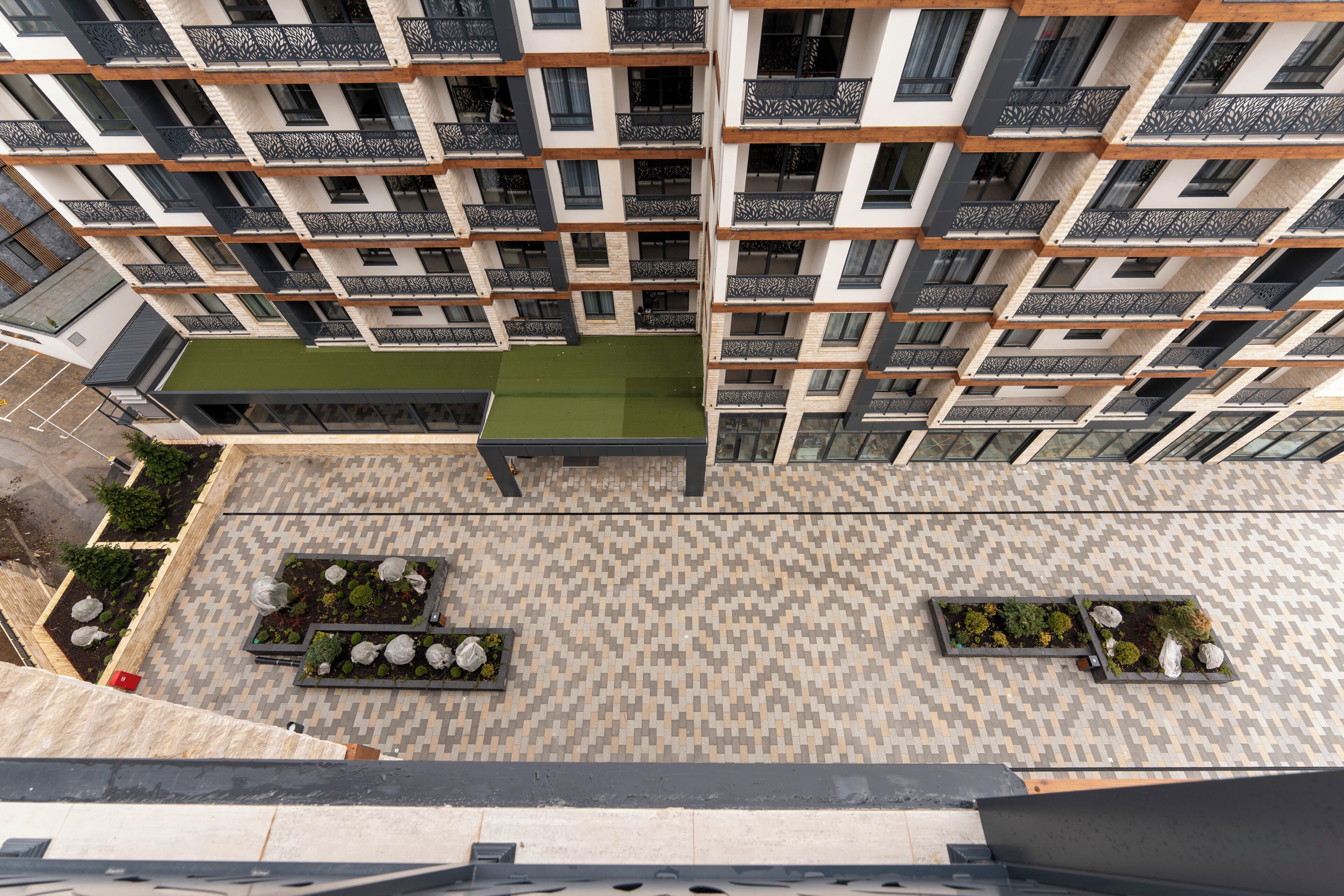 Un immeuble résidentiel à plusieurs étages, doté de balcons, d’un jardin sur le toit et d’un revêtement de sol à motifs.