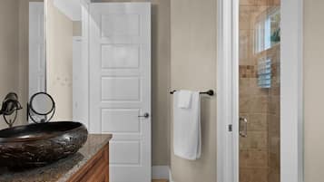 A bathroom with a granite countertop, a white door, and a shower area.