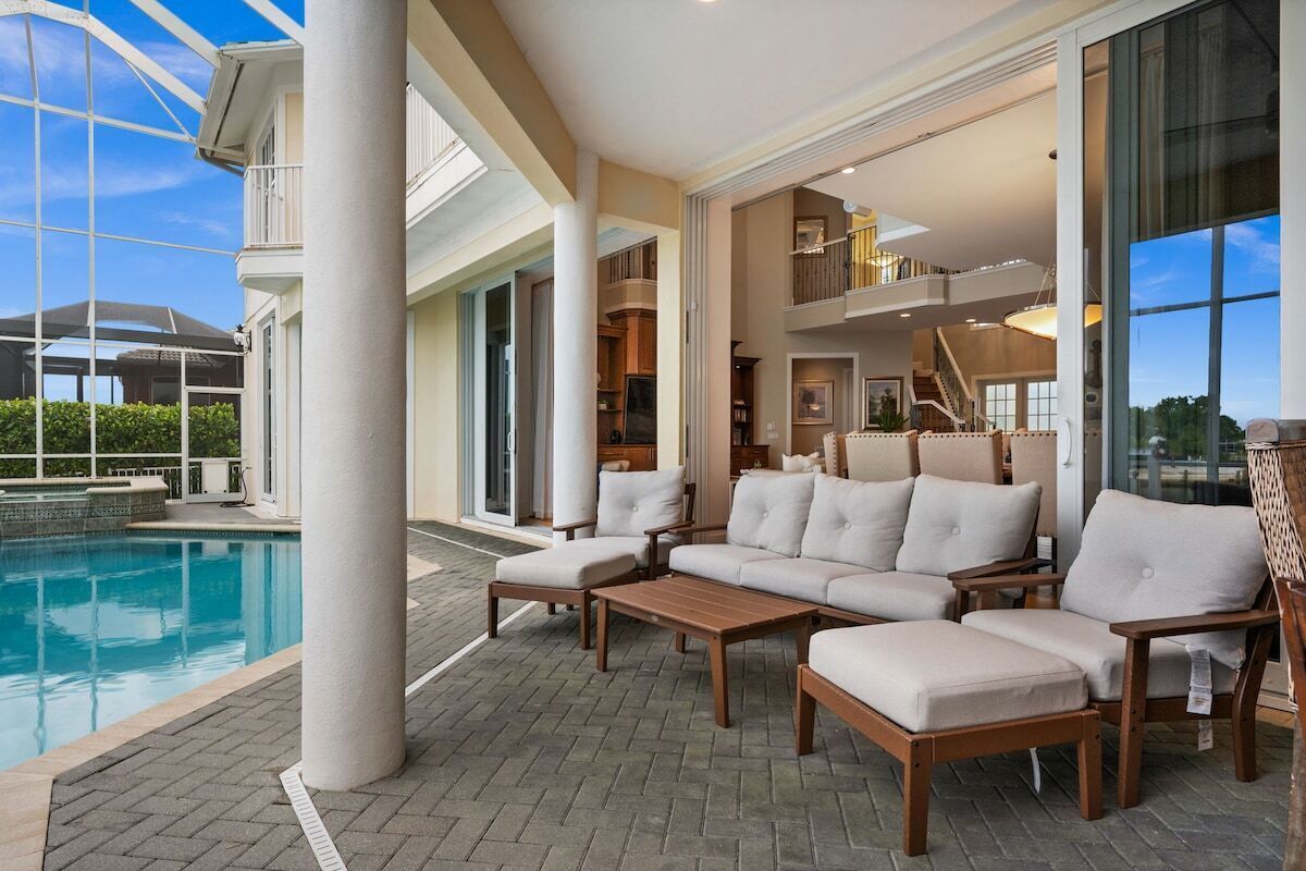 A poolside area with a sectional sofa, a wooden table, and a glass-enclosed space.