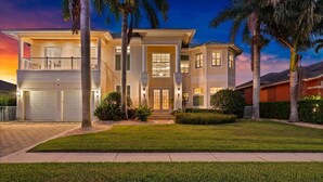 A two-story house with a front entrance, a garage, and a well-maintained lawn. - Waterfront Estate • Rooftop • Heated Pool/Spa (Marco Island)