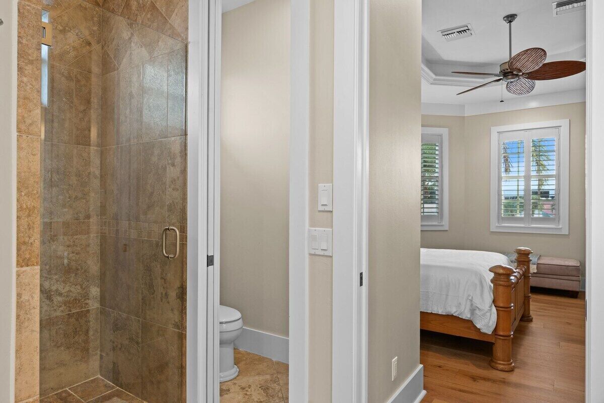 A bathroom with a shower, toilet, and a bed with a wooden headboard.
