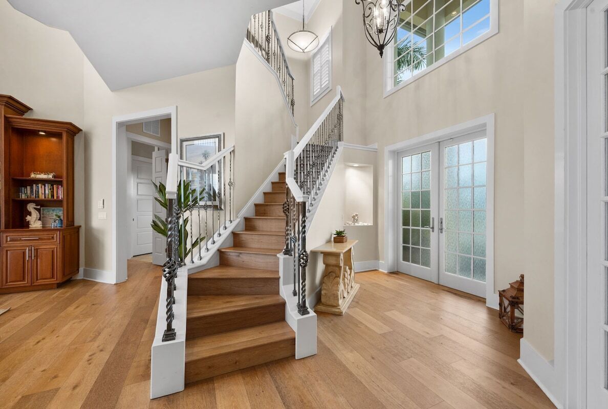 Grand sunlit foyer with elegant staircase and soaring ceilings
