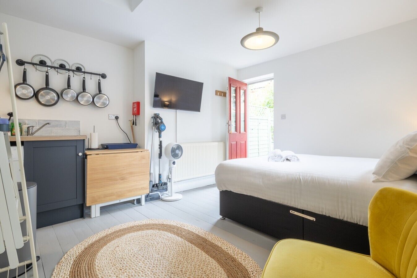 A bedroom with a bed, a bedside table, a chair, a TV, and a window.