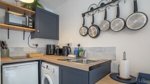 Een kleine keuken met een wasmachine, een magnetron en een koffiezetapparaat.