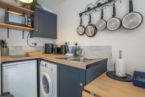 Eine kleine Küche mit Waschmaschine, Mikrowelle und Kaffeemaschine.