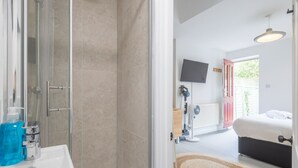 Een badkamer met een douche, wastafel en een fles blauwe vloeistof.