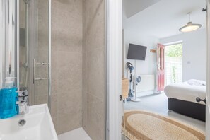 Ein Badezimmer mit Dusche, Waschbecken und einer Flasche mit blauer Flüssigkeit.