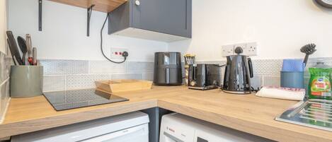 Cozinha compacta com uma lava-louças Bosch, cafeteira e chaleira no balcão.