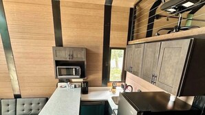 A compact kitchen with a microwave, a refrigerator, and a built-in oven.