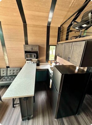 A compact kitchen with a microwave, a refrigerator, and a built-in oven.