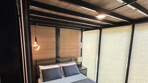 A modern bedroom with a bed, bedside tables, and a hanging light fixture.