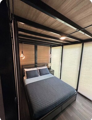 A modern bedroom with a bed, bedside tables, and a hanging light fixture.