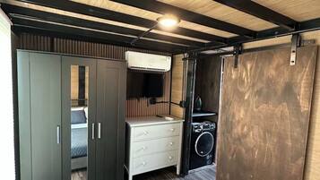 A compact room with a bed, wardrobe, and a washing machine.