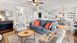 A spacious living room with a blue sofa, two armchairs, a coffee table, and a ceiling fan. - Waterfront Condo | King Bed | Walk to Douglas (Douglas)