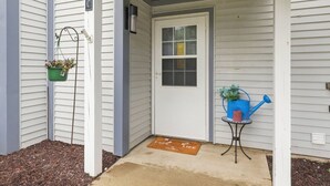 A house entrance with a door, a mailbox, a small table with a watering can, and a potted plant. - Waterfront Condo | King Bed | Walk to Douglas (Douglas)
