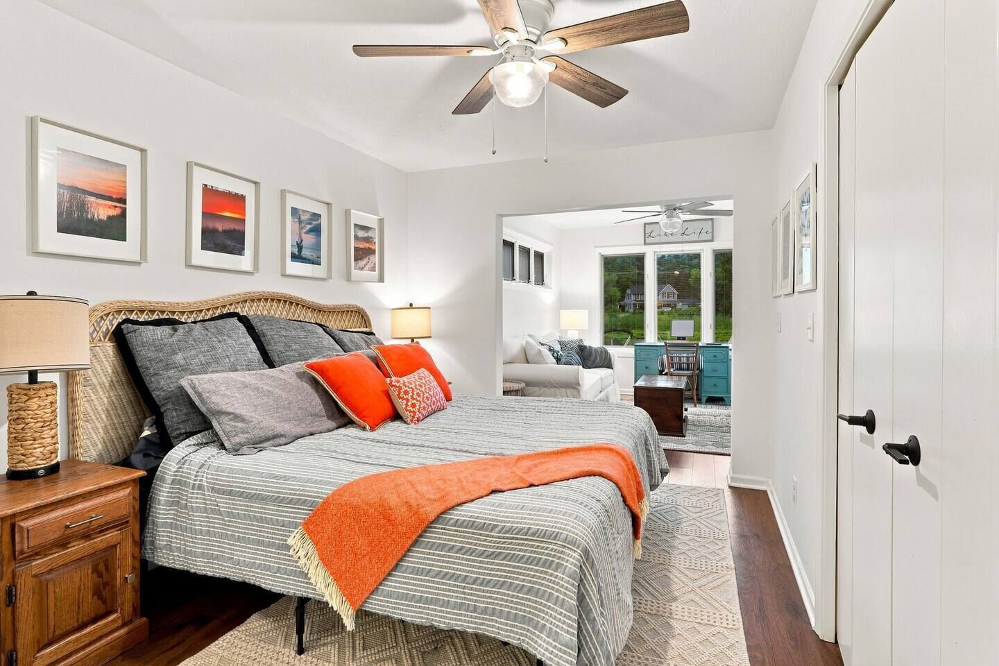 A bedroom with a bed, bedside tables, a ceiling fan, and framed pictures on the wall.