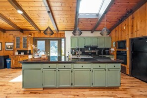 A spacious kitchen with a central island, wooden cabinetry, and a skylight.
