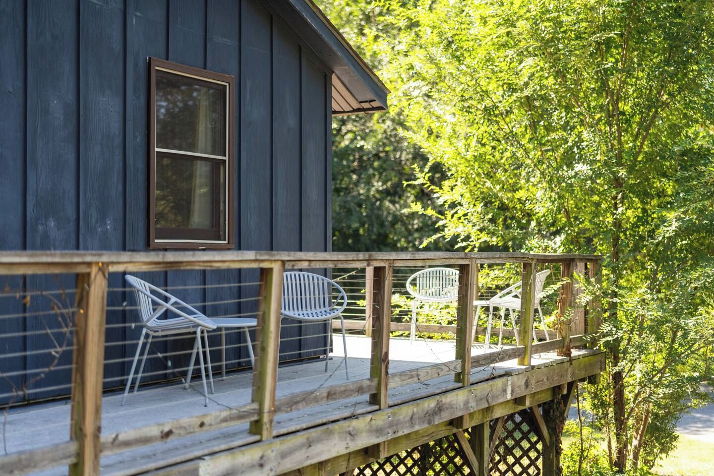 A wooden deck with metal chairs and a wooden railing.