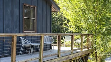 A wooden deck with metal chairs and a wooden railing.