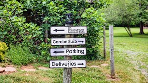 A directional signpost with arrows pointing to various hotel suites and services.