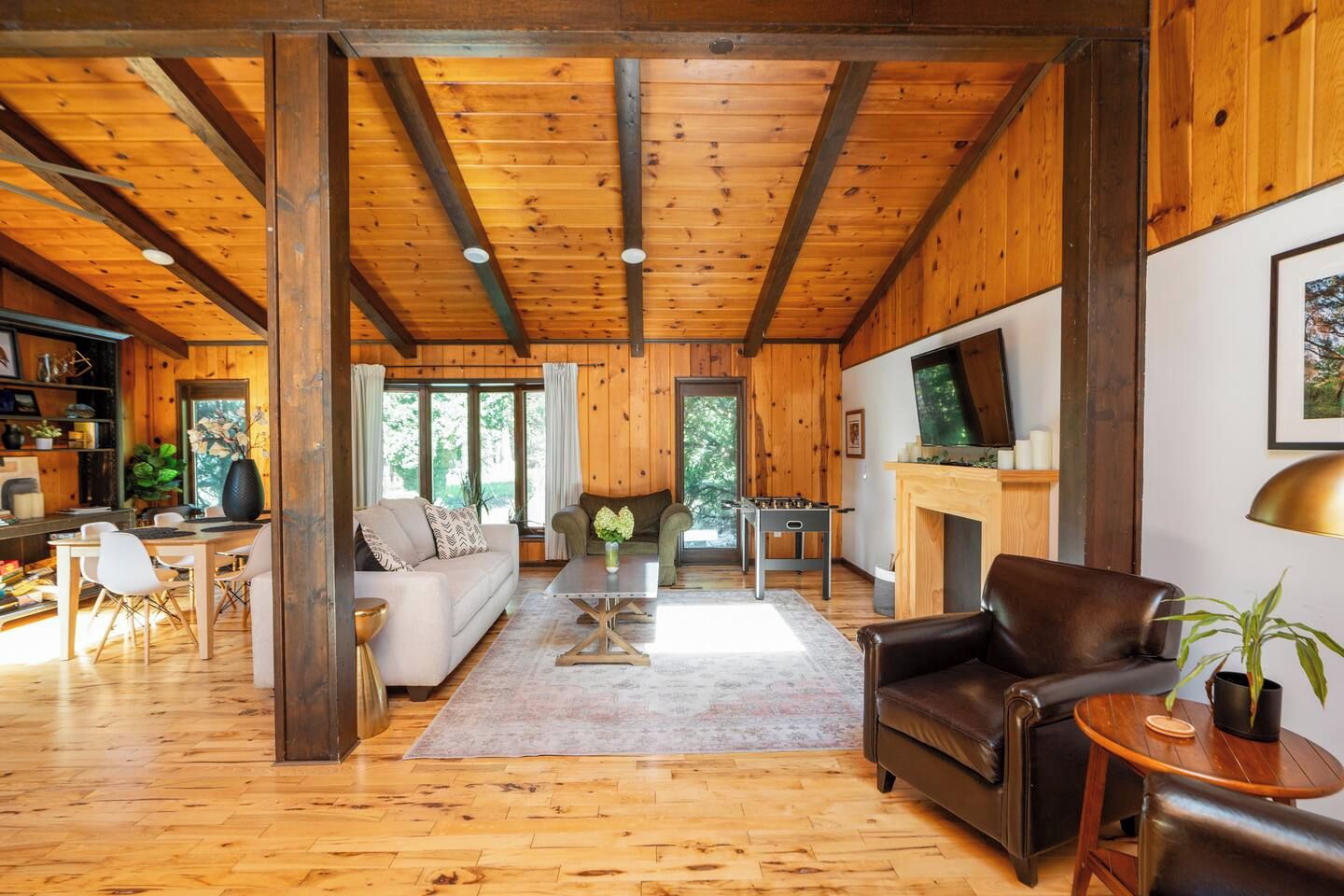 Ein geräumiger Wohnbereich mit Holzböden und hoher Decke, mit einer Couch, einem Couchtisch, einem Kamin und einem Fernseher.