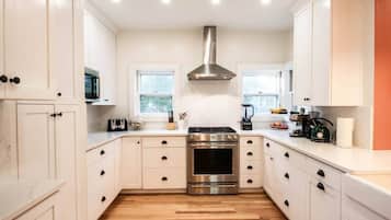 Une cuisine moderne avec des armoires blanches, une hotte en acier inoxydable et un plancher en bois.