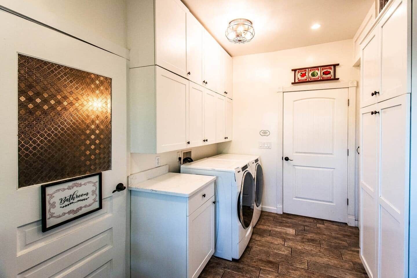 A compact laundry room with a washing machine, dryer, and a framed sign on the wall.