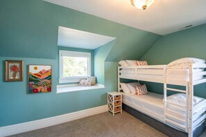 A room with a bunk bed, a window with a view, and two framed artworks on the wall.