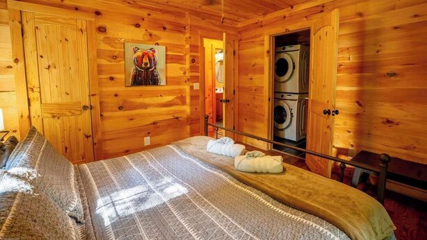 Quarto de cabana de madeira com uma cama, um quadro e uma máquina de lavar.