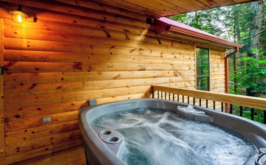 Eine Holzhütte mit Whirlpool auf der Veranda.