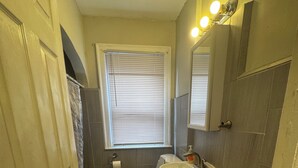 A compact bathroom with a toilet, sink, and window with blinds. - Adorable 2-bedroom apartment with AC in cool Detroit (Detroit)