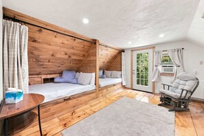 Une chambre mansardée chaleureuse, avec un plafond en pente, une petite table, une chaise et une vue sur la verdure.