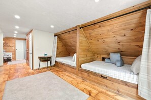 Een knus slaapkamer met houten wanden, een schuin dak en een klein nachtkastje met een lamp.