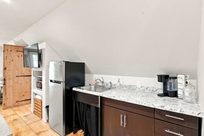 Een moderne keuken met een ingebouwde magnetron, een roestvrijstalen koelkast, een wastafel met een kraan en een koffiezetapparaat.